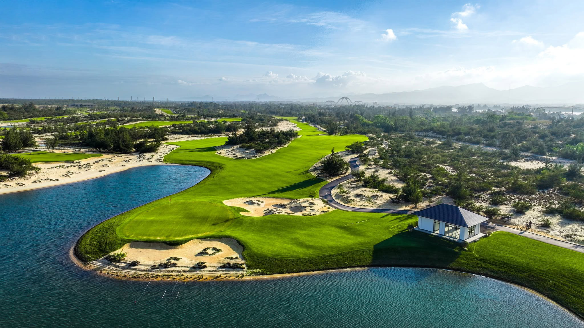 Blue Diamond Golf Links is situated on the Bao Ninh Peninsula in Dong Hoi Ward, Quang Tri Province, offering golfers a distinctive coastal golfing experience with a classic links-style design. The course embraces the natural beauty of the seaside landscape, featuring rolling sand dunes, wide-open spaces, and panoramic ocean views. Exposed to coastal winds and built on firm, sandy terrain, the course allows for longer ball rolls while demanding greater precision and control from players. Deep bunkers, uneven terrain, and constantly changing wind conditions add complexity to each round. The natural sea breeze can significantly influence ball direction and distance, making club selection and shot execution essential to navigating the course successfully. Blue Diamond Golf Links