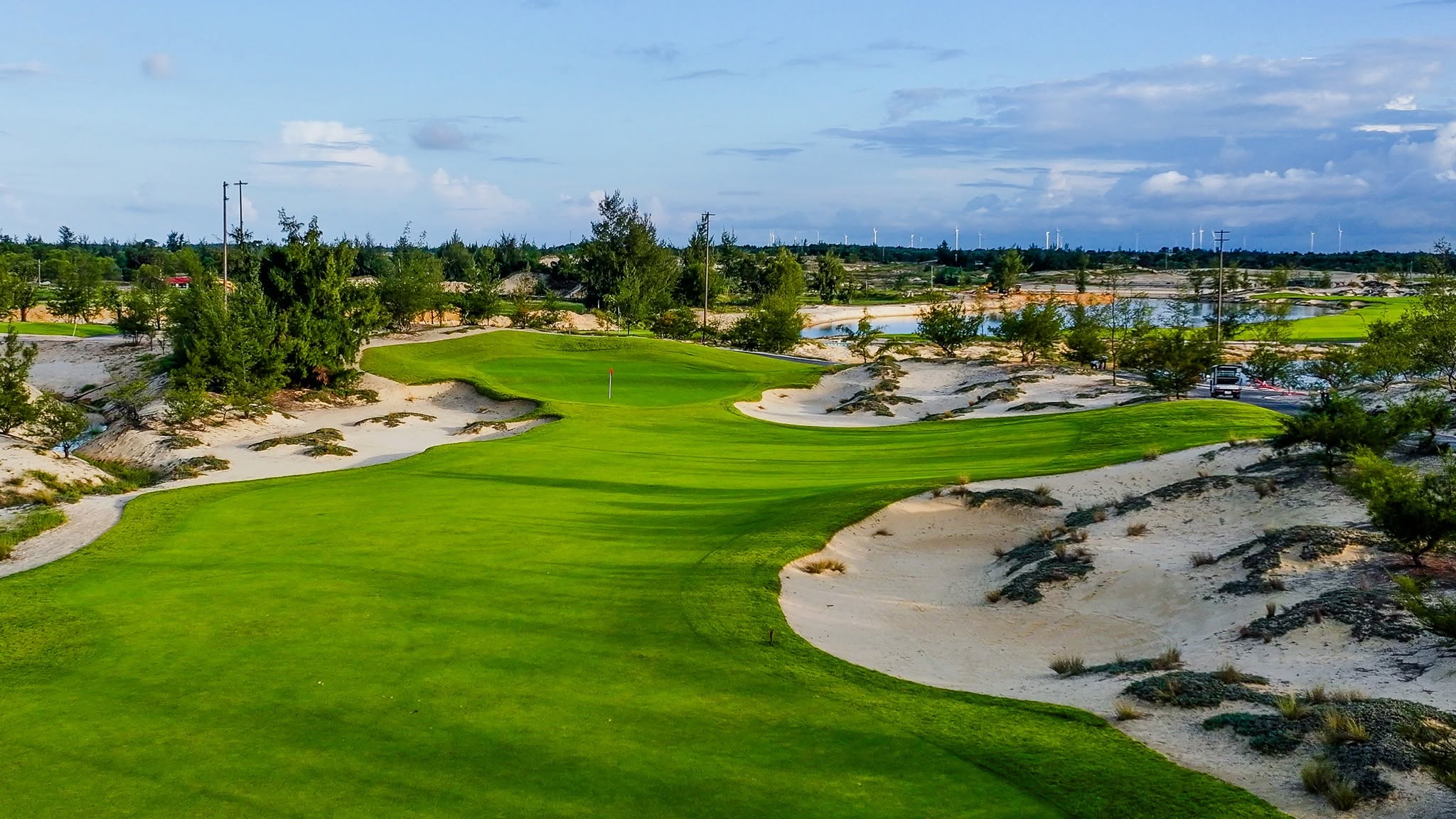 Blue Diamond Golf Links is situated on the Bao Ninh Peninsula in Dong Hoi Ward, Quang Tri Province, offering golfers a distinctive coastal golfing experience with a classic links-style design. The course embraces the natural beauty of the seaside landscape, featuring rolling sand dunes, wide-open spaces, and panoramic ocean views. Exposed to coastal winds and built on firm, sandy terrain, the course allows for longer ball rolls while demanding greater precision and control from players. Deep bunkers, uneven terrain, and constantly changing wind conditions add complexity to each round. The natural sea breeze can significantly influence ball direction and distance, making club selection and shot execution essential to navigating the course successfully. Blue Diamond Golf Links